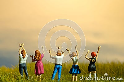 Miniature tiny people toys photography. Group of teens raised hand or hands up celebration at meadow land Stock Photo