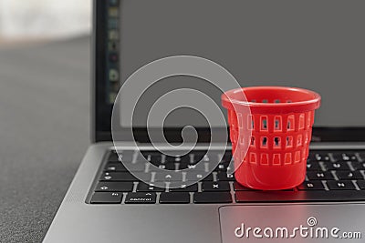 Miniature toy trash can on laptop keyboard. Concept of deleting files and cleaning up information garbage. Cleaning and Stock Photo