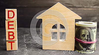 Miniature wooden house, dollars and the inscription ` Debt `. Real estate, home savings, loans market concept. Payment of real est Stock Photo