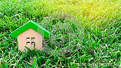 Miniature wooden house on grass. Real estate concept. Eco-friendly and energy efficient house. Buying a home outside the city. The Stock Photo