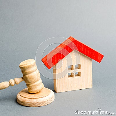 Miniature wooden house and judge`s hammer. The concept of resolving property disputes. Property alienation. Confiscated housing. Stock Photo