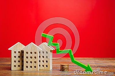 Miniature wooden houses and a green arrow down. The concept of low cost real estate. Lower mortgage interest rates. Falling prices Stock Photo