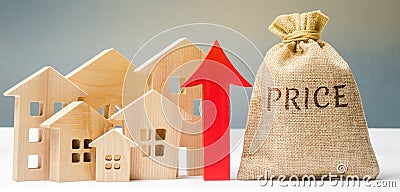 Miniature wooden houses, a money bag with the word Price and an up arrow. The concept of increasing housing prices. Rising rent. Stock Photo