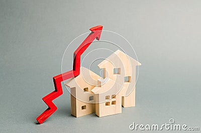 Miniature wooden houses and red arrow up. The concept of increasing the cost of housing. High demand for real estate. The growth Stock Photo