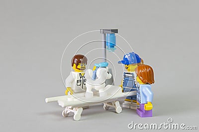 Minifigure of Veterinarian examining sick white French Poodle on a bed at the clinic with his owners watching him and concerned Editorial Stock Photo