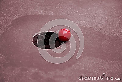 Minigolf ball a step before falling into the minigolf hole Stock Photo