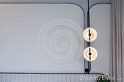 Minimal bedroom corner with circular wall lamp installed on the wall with beige wallcovering in natural light setting scene / Stock Photo
