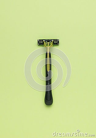 The minimal composition is a black and green men`s razor on a green background. The central composition. Flat lay Stock Photo