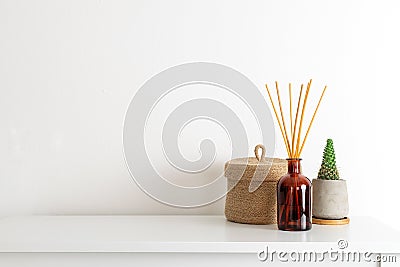 Scandinavian nordic hygge style, home interior - candle, scent aroma diffuser, small straw basket, white shelf Stock Photo