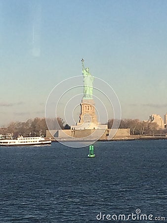 Minimal seascape view of the Statue of Liberty silhouette in the horizon, wide blue and yellow foggy sky in background, Staten Stock Photo