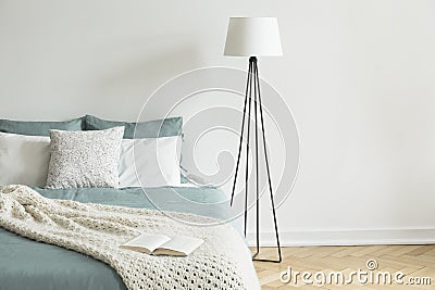 Minimal and simple white wall and parquet bedroom interior with a bed and a lamp. Empty space. Real photo. Stock Photo