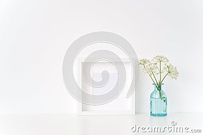 Minimal white square frame mock up with a Aegopodium in transparent blue vase. Mockup for quote, promotion, headline Stock Photo