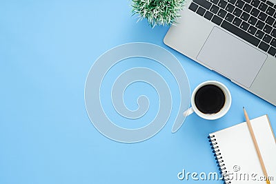 Top view office desk with laptop, notebooks and coffee cup on blue color background. Stock Photo