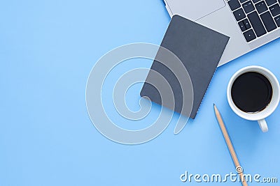 Creative flat lay photo of workspace desk. Top view office desk with laptop, notebooks and coffee cup on blue color background. Stock Photo