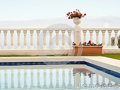 Minimalism of form and color, a terraced white space with a white pot with dark red geraniums against whitish sky Stock Photo