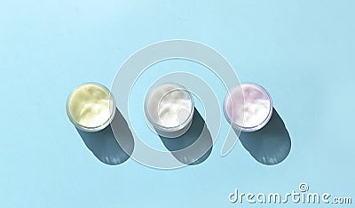 Minimalist cosmetic concept with three cream glass in row on blue background. Stock Photo