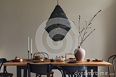 Minimalist rustic concept of dining room interior with wooden family table, design retro chairs, teapot, tableware, decoration. Stock Photo