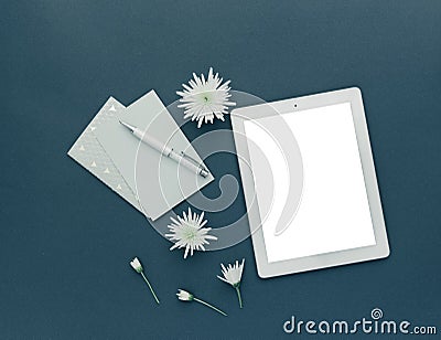 Minimalist workspace. Tablet with spring flowers on pastel background. Stock Photo