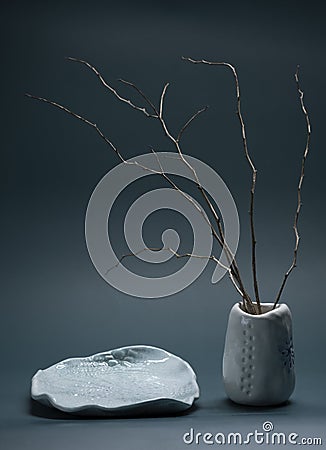 Minimalistic composition in Japanese Asian style with ikebana in an earthenware clay handmade vase and plate Stock Photo