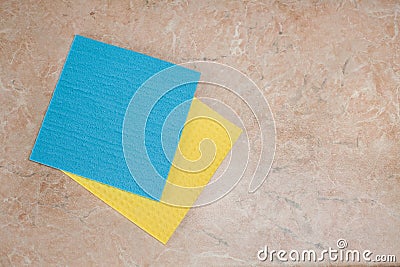 A minimalistic composition of yellow and blue kitchen rags lying on a textured tabletop Stock Photo