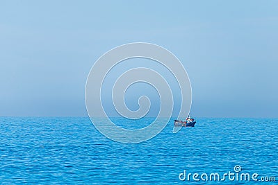 Minimalistic image of the sea with a fishing boat. Blue sea water and clear sky Stock Photo