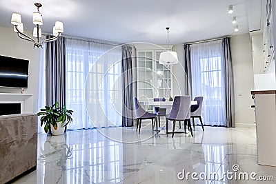 Minimalistic interior of living room in light tone with marble flooring, large windows and a table for four persons Stock Photo