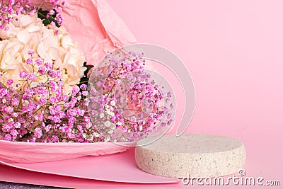 A minimalistic scene of a lying stone with a bouquet of hydrangea flowers on a light pink background. Stock Photo