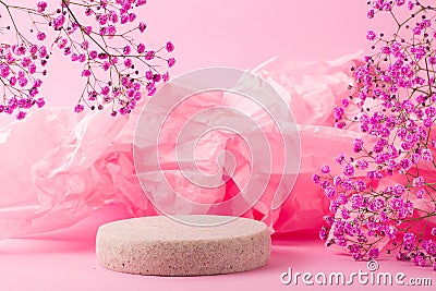 Minimalistic scene of a lying stone with flowers and fabric on a light pink background. Stock Photo