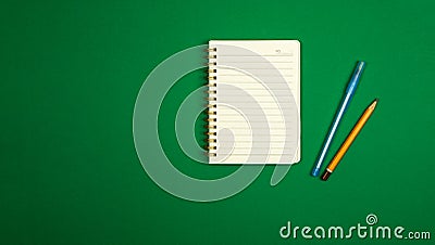 Minimalistic simple workspace design with notepad, pen and pencil, green background, top view, copy space banner Stock Photo