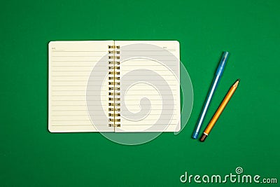 Minimalistic simple workspace design with notepad, pen and pencil, green background, top view, copy space Stock Photo