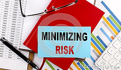 MINIMIZING RISK text on sticky on red notebook on chart background Stock Photo