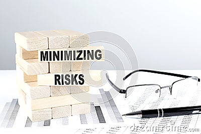 MINIMIZING RISKS is written on wooden blocks on a chart background Stock Photo