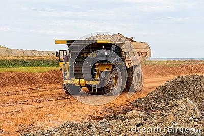 A mining dump truck drives and unloads bauxite minerals Editorial Stock Photo