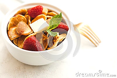 Minipancakes breakfast - white bowl with strawberries and pancakes, mik jar, honey, fresh mint and house plant. Lifestyle morning Stock Photo