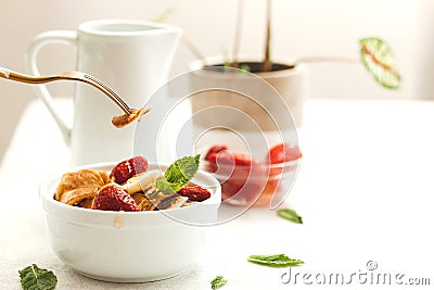 Minipancakes breakfast - white bowl with strawberries and pancakes, mik jar, honey, fresh mint and house plant. Lifestyle morning Stock Photo