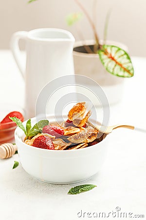 Minipancakes breakfast - white bowl with strawberries and pancakes, mik jar, honey, fresh mint and house plant. Lifestyle morning Stock Photo