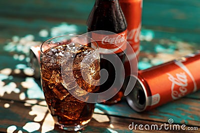 MINSK, BELARUS-AUGUST 25, 2016. Can and a glass of iced Coca-Cola on a wooden table Editorial Stock Photo