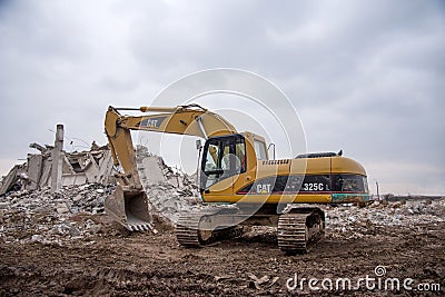Excavator CATERPILLAR 325CL at demolition of tall building. Hydraulic machine for demolish. Backhoe Editorial Stock Photo