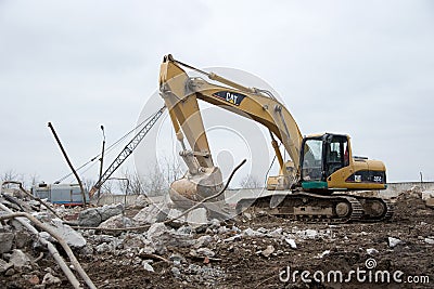 Excavator CATERPILLAR 325CL at demolition of tall building. Hydraulic machine for demolish. Backhoe Editorial Stock Photo