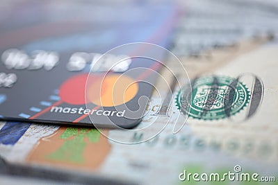 Embossed chipped mastercard credit card and hundred dollar bank notes closeup Editorial Stock Photo