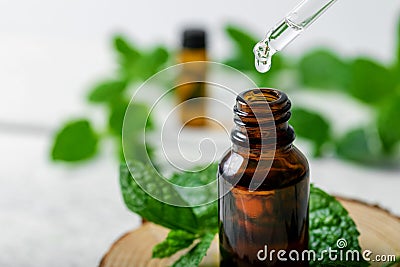 Mint essential oil drop falling from dropper into the bottle Stock Photo