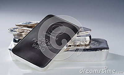 Minted silver bars and coins against a blue gray background Stock Photo
