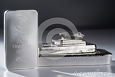 Minted silver bars and coins against a gray background Stock Photo