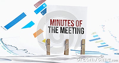 MINUTES OF THE MEETING text on paper sheet with chart, dice, spectacles, pen, laptop and blue and yellow push pin on wooden table Stock Photo