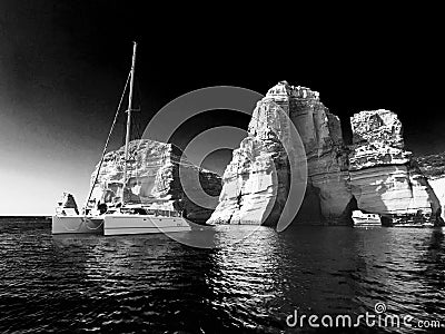A miraculous black and white view and out-of-this-world view of yachts and the unique geology of Milos, a beautiful Greek island Stock Photo