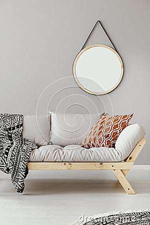 Mirror above scandinavian settee with patterned pillow and blanket Stock Photo