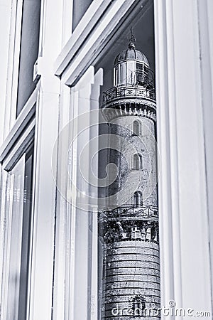 Mirroring of the old lighthouse of Rostock Warnemuende in a window glass, monochrome Stock Photo