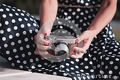 Oldschool mirrorless camera in the hands of a girl in a white and black dot dress Stock Photo