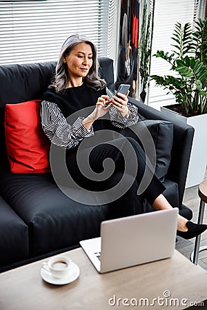 Smiling mature woman at work with gadgets stock photo Stock Photo