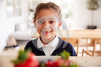 Mischievous Girl Wearing School Uniform Taking Strawberry From Kitchen Counter Stock Photo